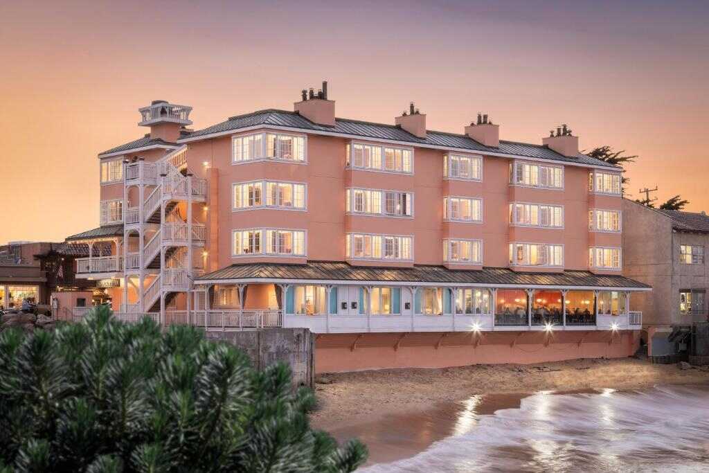 Charming pink beach hotel in California with ocean views and sunset backdrop.