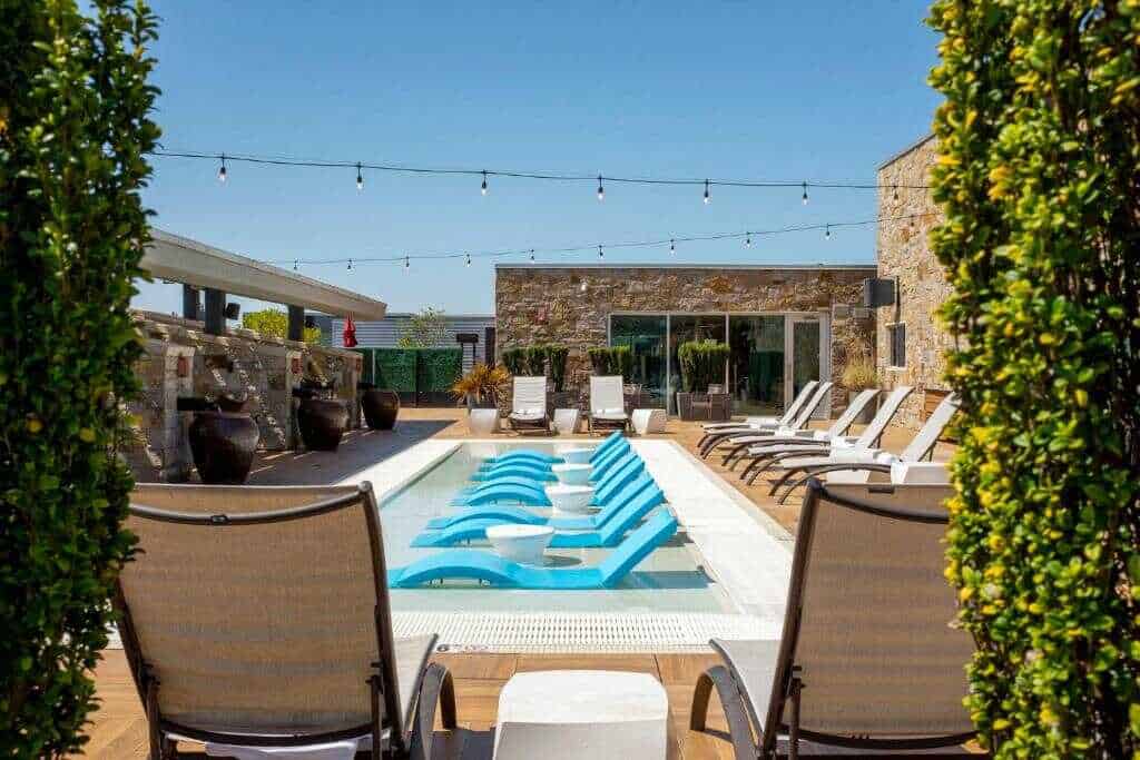 Modern rooftop pool with lounge chairs and string lights at California Nomad.