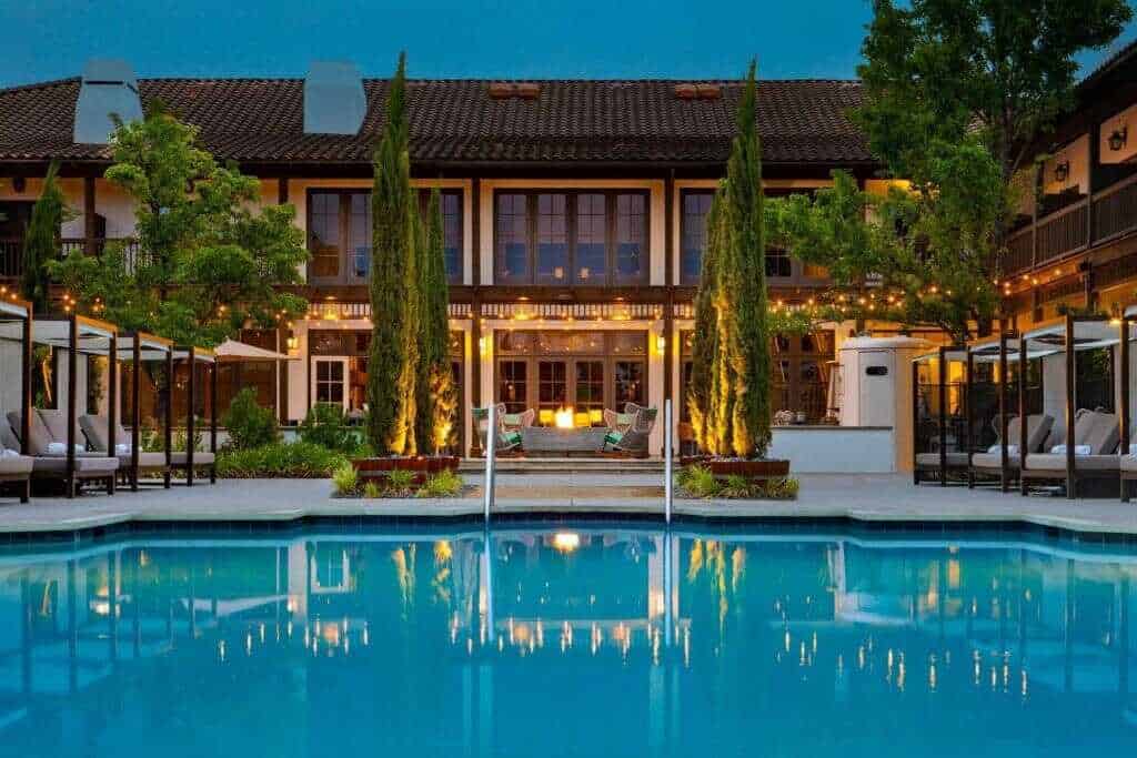 Elegant hotel courtyard with pool, lush greenery, and cozy outdoor seating in California.