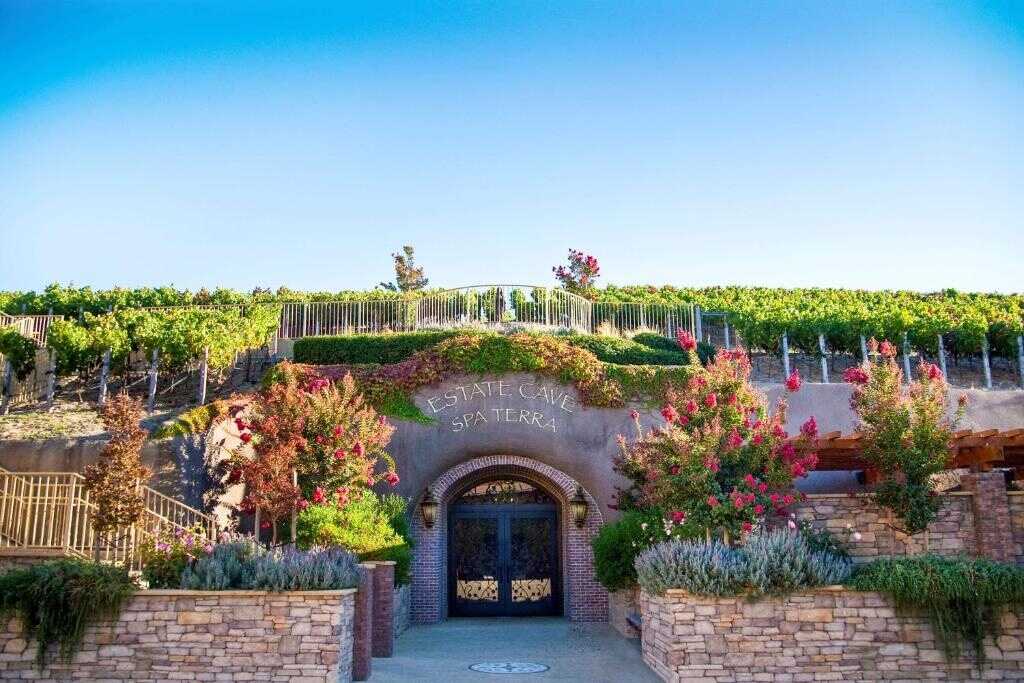 Vineyard estate entrance with lush greenery and colorful flowers, California Nomad winery and wine tasting venue.