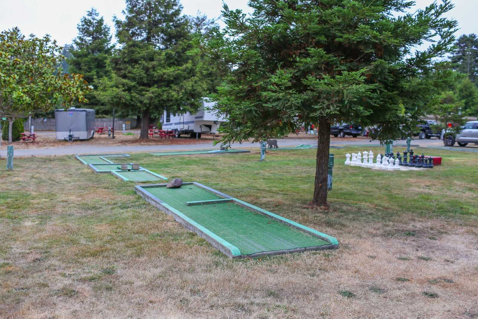 Mini golf course in a scenic campground surrounded by trees and RVs in California.