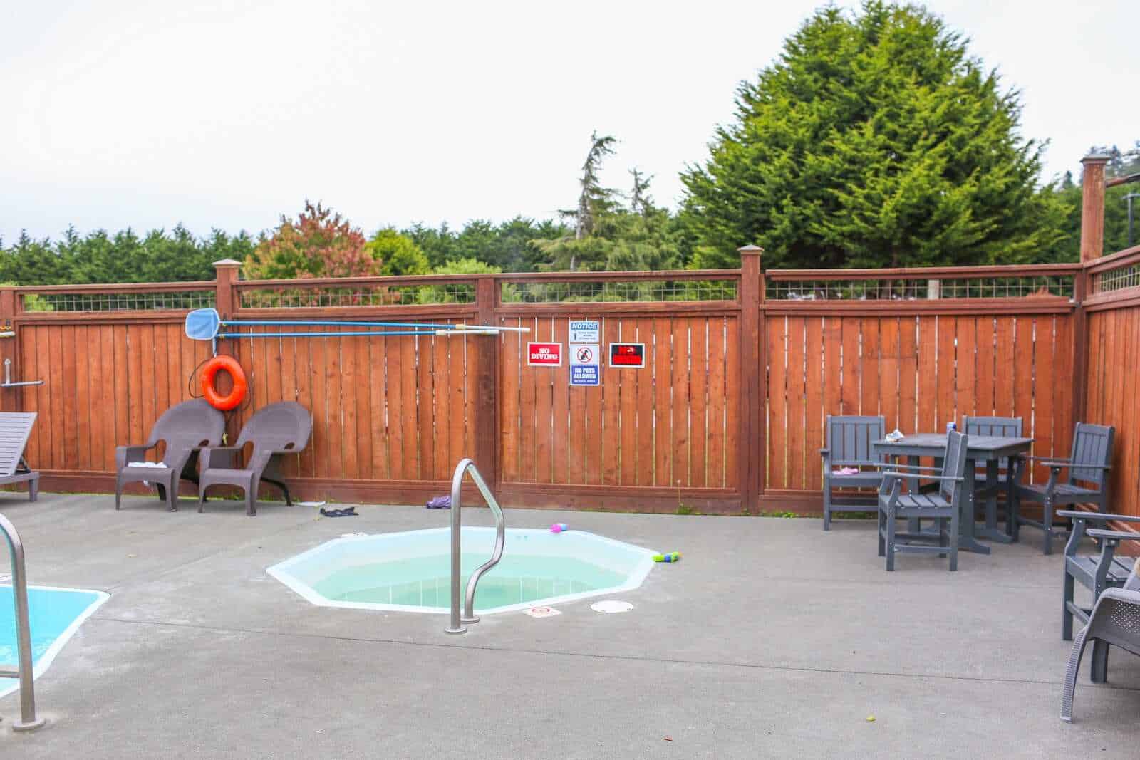 Sunny backyard with hot tub, outdoor seating, and wooden privacy fence, perfect for relaxation and outdoor living.