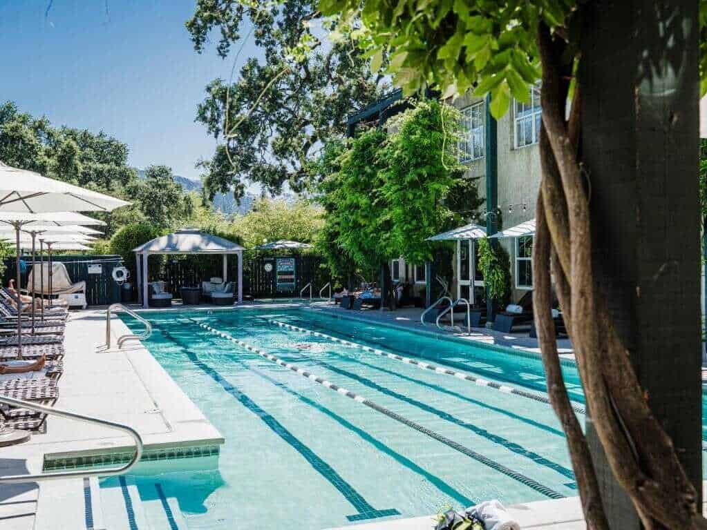 Serene outdoor swimming pool with lounge chairs and umbrellas in a lush, green setting.