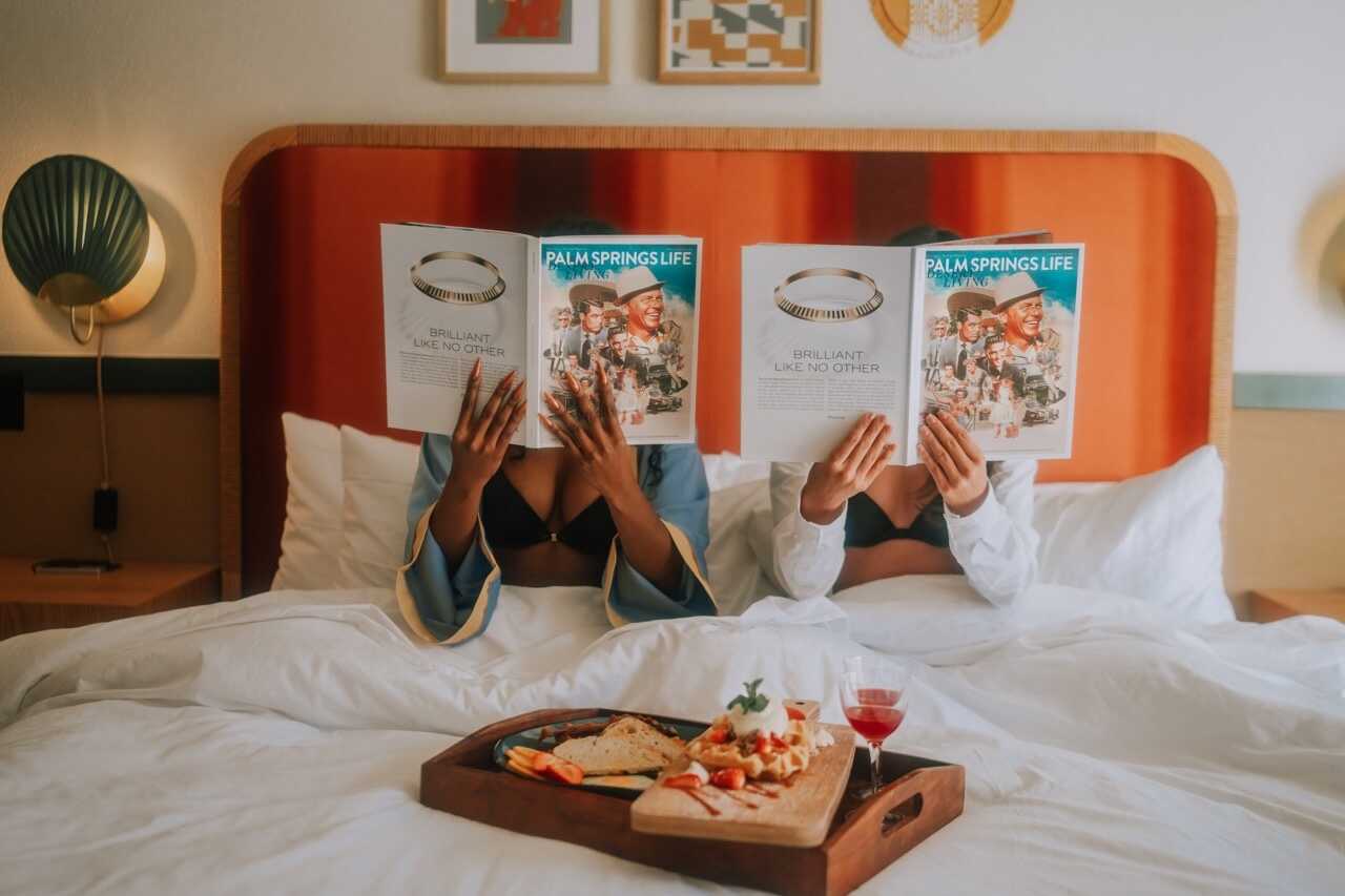 Magazine reading in a hotel room with breakfast tray on bed - California Nomad.