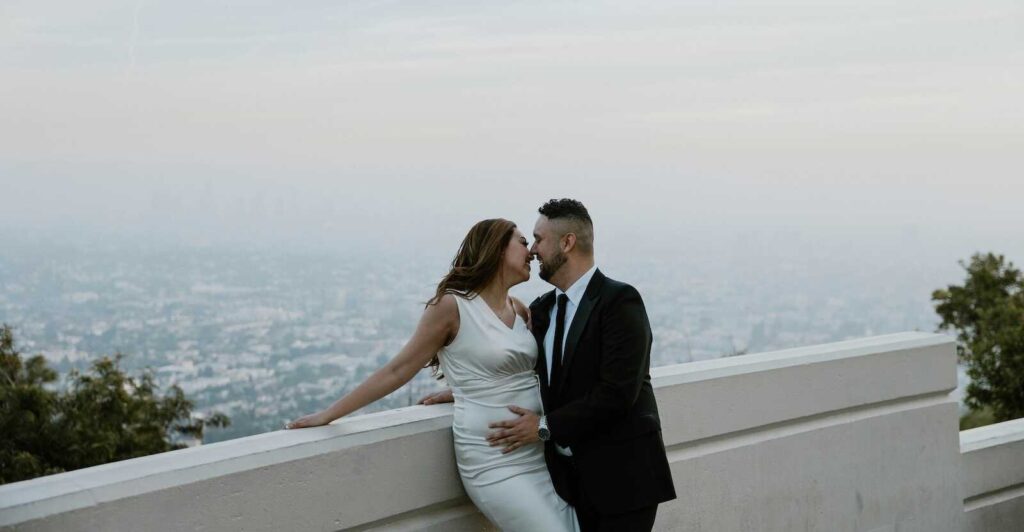 Couple embracing at Griffith Observatory overlook for Los Angeles engagement photos.