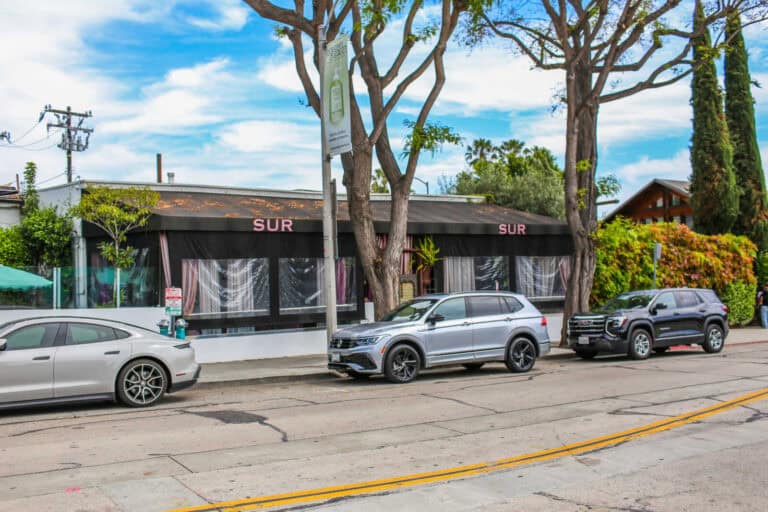 Exterior view of SUR in West Hollywood with parked cars along the street.